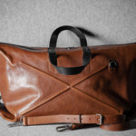 Brown leather bag with black handle on a gray background