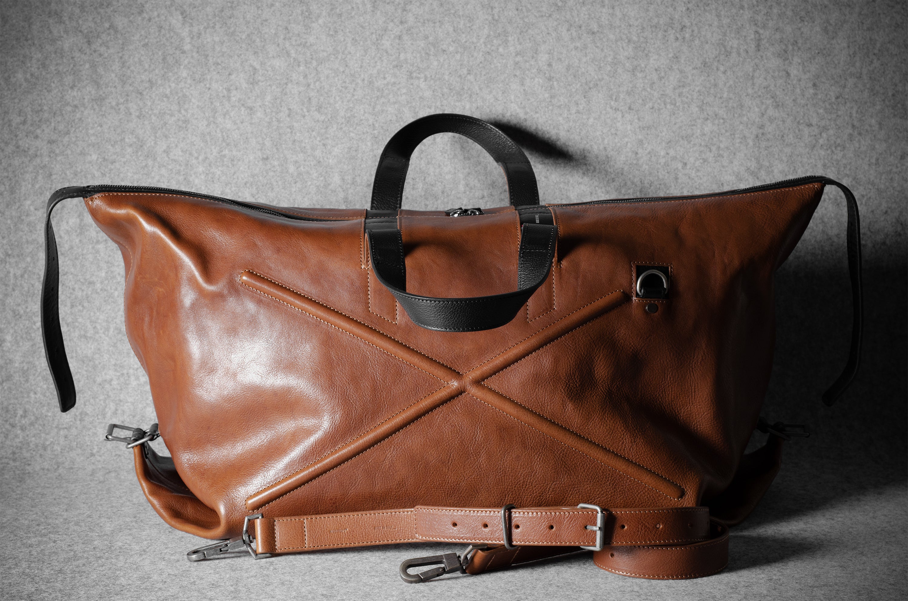 Brown leather bag with black handle on a gray background