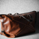 Brown leather duffel bag on a textured gray background