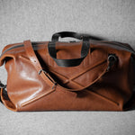 Brown leather duffel bag on a gray background