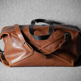 Brown leather duffel bag on a gray background