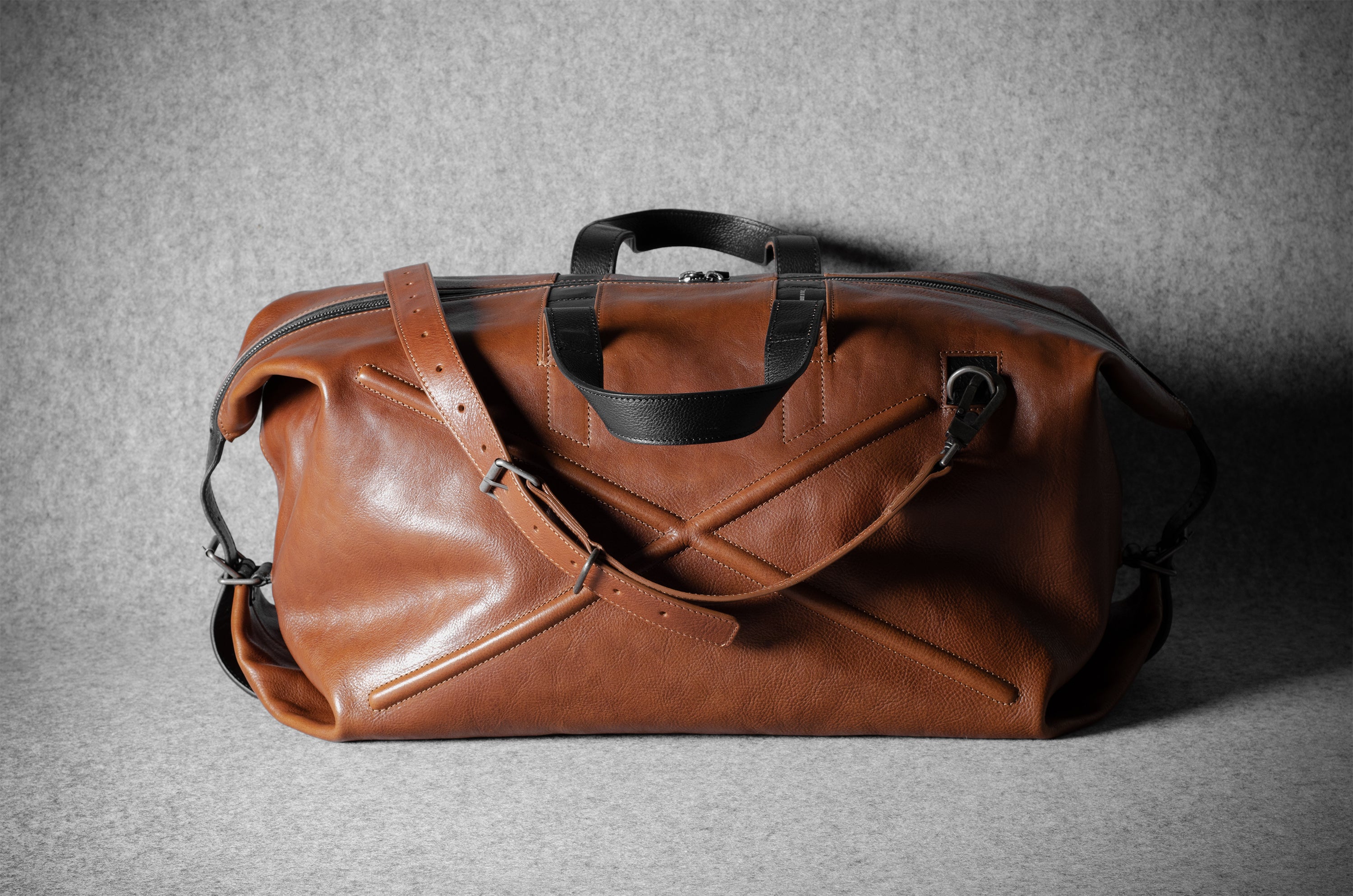 Brown leather duffel bag on a gray background