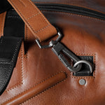 Close-up of a brown leather bag with a metal buckle.