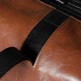 Close-up of a brown leather bag with a black strap