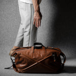Brown leather duffel bag on a gray background