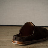 A Brown suede slipper on a wooden background.