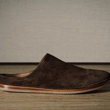 A Brown suede slipper on a wooden background.