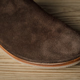A Brown suede slipper on a wooden background.
