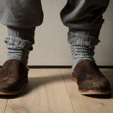 Pair of brown suede slippers on a wooden background.