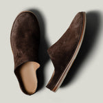 Pair of brown suede slippers on a light gray background