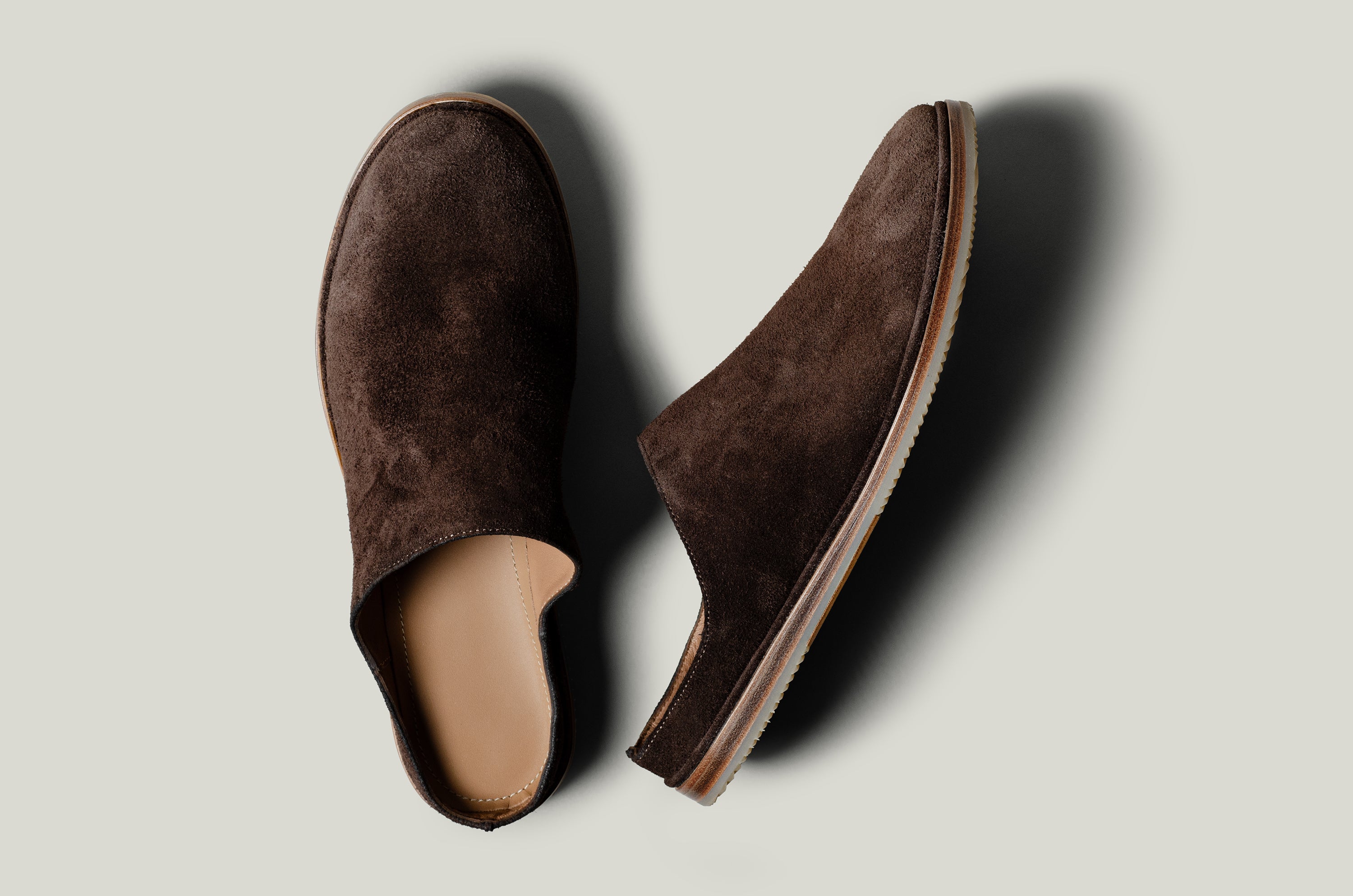 Pair of brown suede slippers on a light gray background