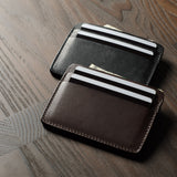 Two card cases on a dark wood background, one in brown, one in black with cards inside.