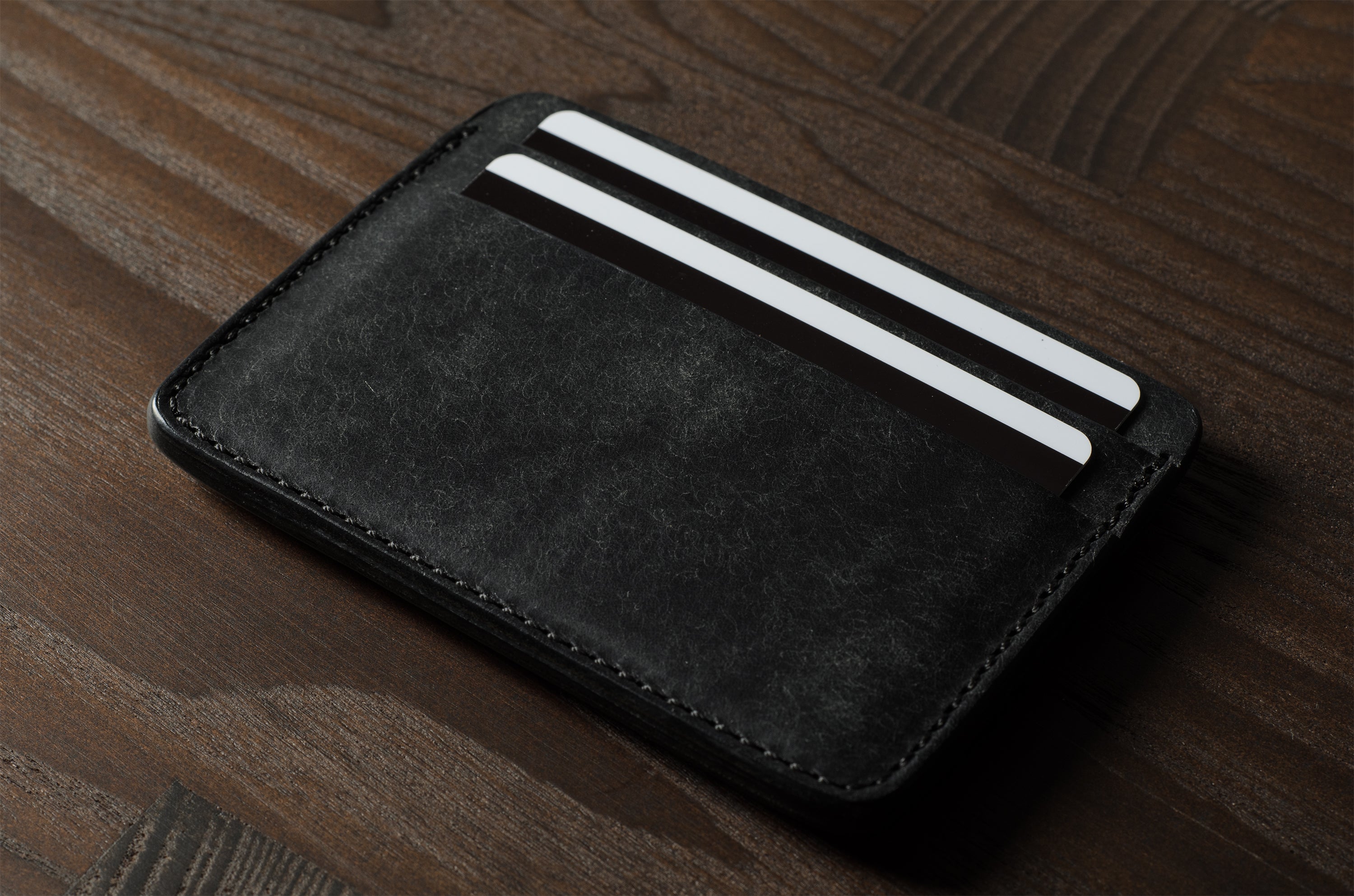 Black cardholder with cards on a wooden surface