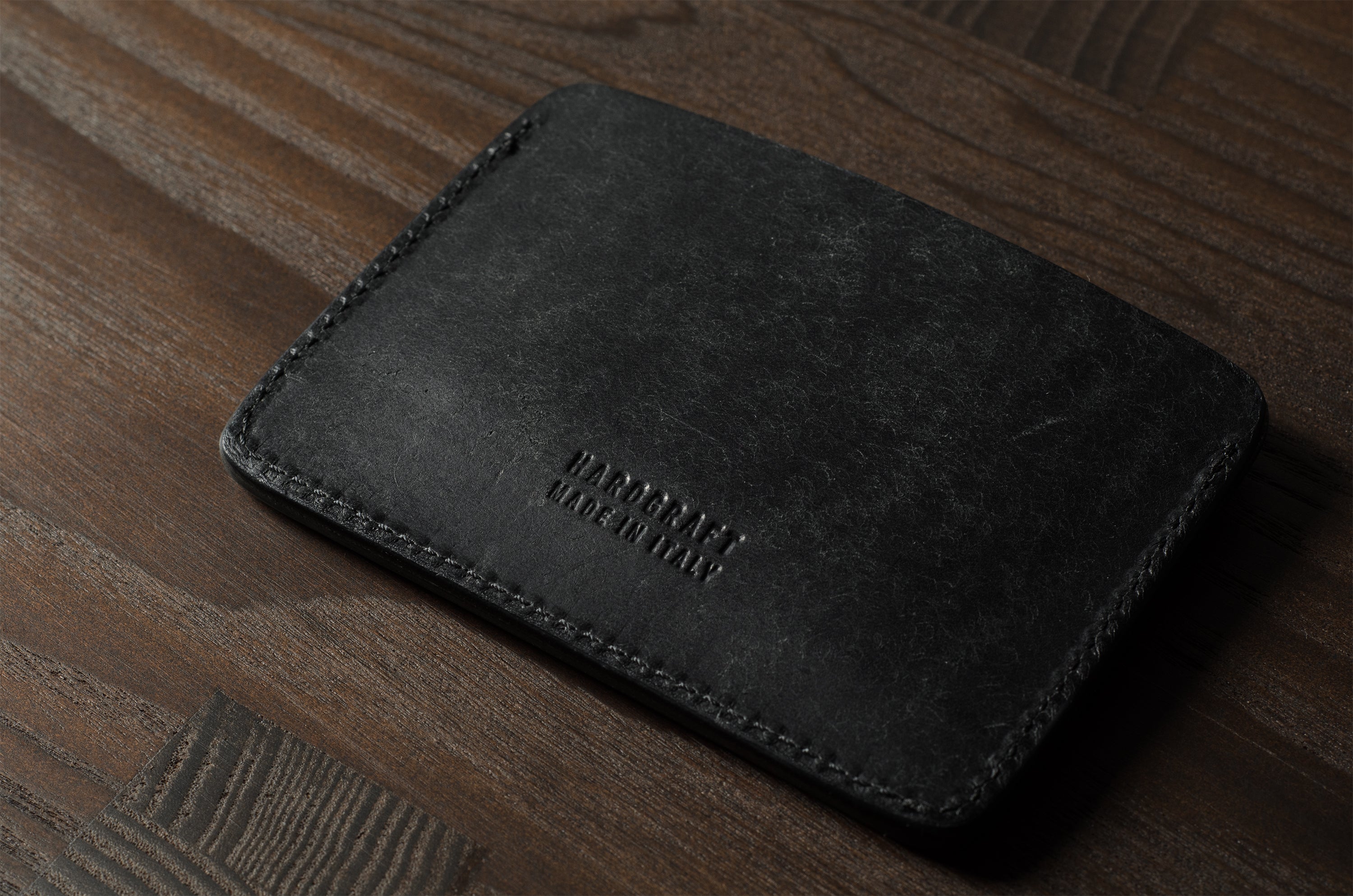 Black leather card case on a wooden surface