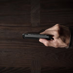 Hand holding a card case on a wooden surface