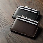 Two card cases on a dark wood background, one in brown, one in black with cards inside.