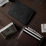 Two card cases on a dark wood background, one in brown, one in black with cards inside.