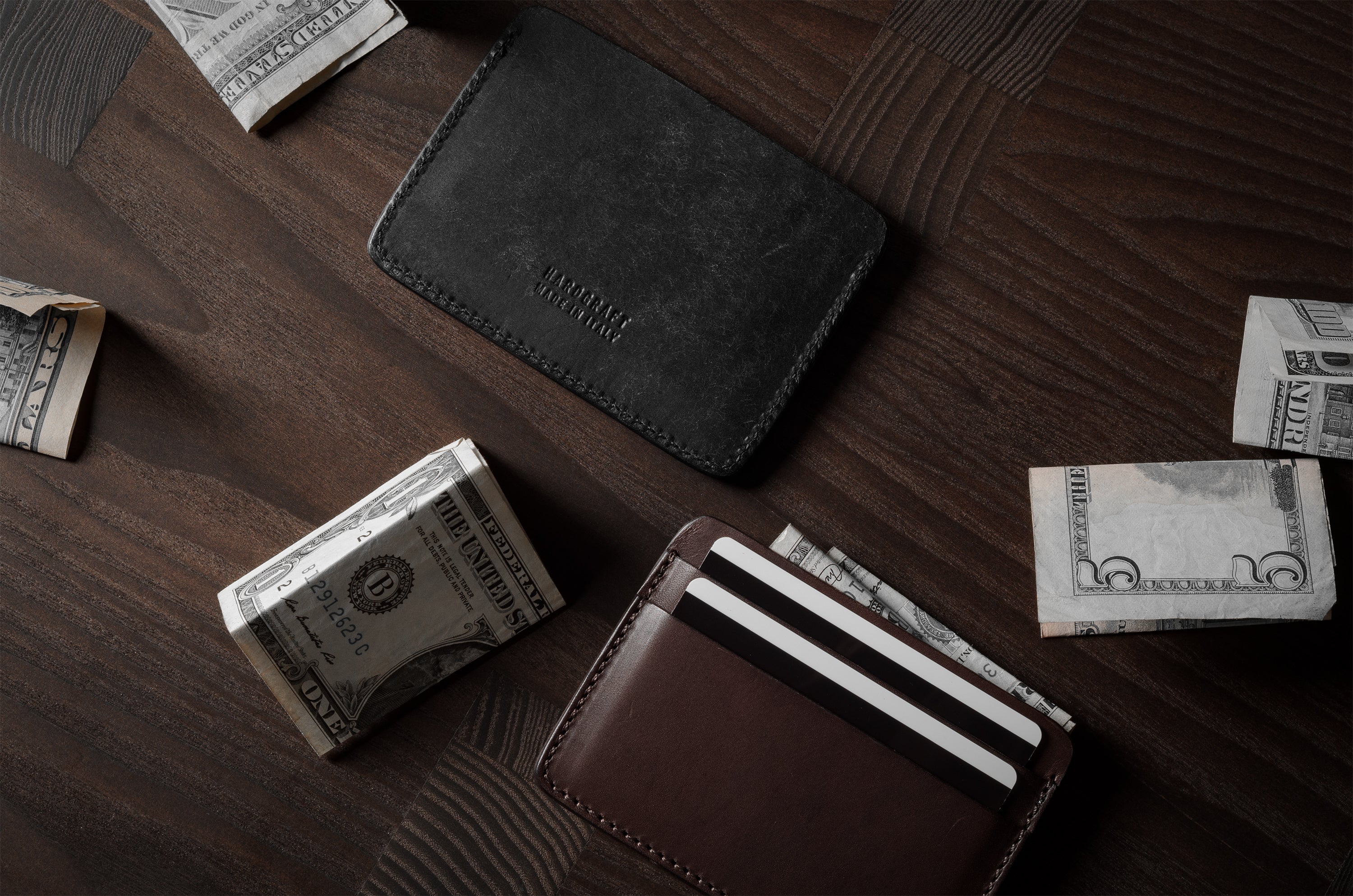 Two card cases on a dark wood background, one in brown, one in black with cards inside.