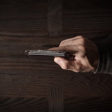 Brown leather card case with cards inside on a dark wood background.
