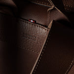 Close-up of a dark brown leather bag showing the interior lining, stitching, and a small red brand tab with white text reading ‘HARDGRAFT MADE IN ITALY'.
