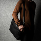 Person holding a black briefcase against a gray background