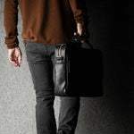 Person holding a black briefcase against a dark background