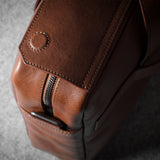 Close-up of a brown leather bag with a zipper on a gray background