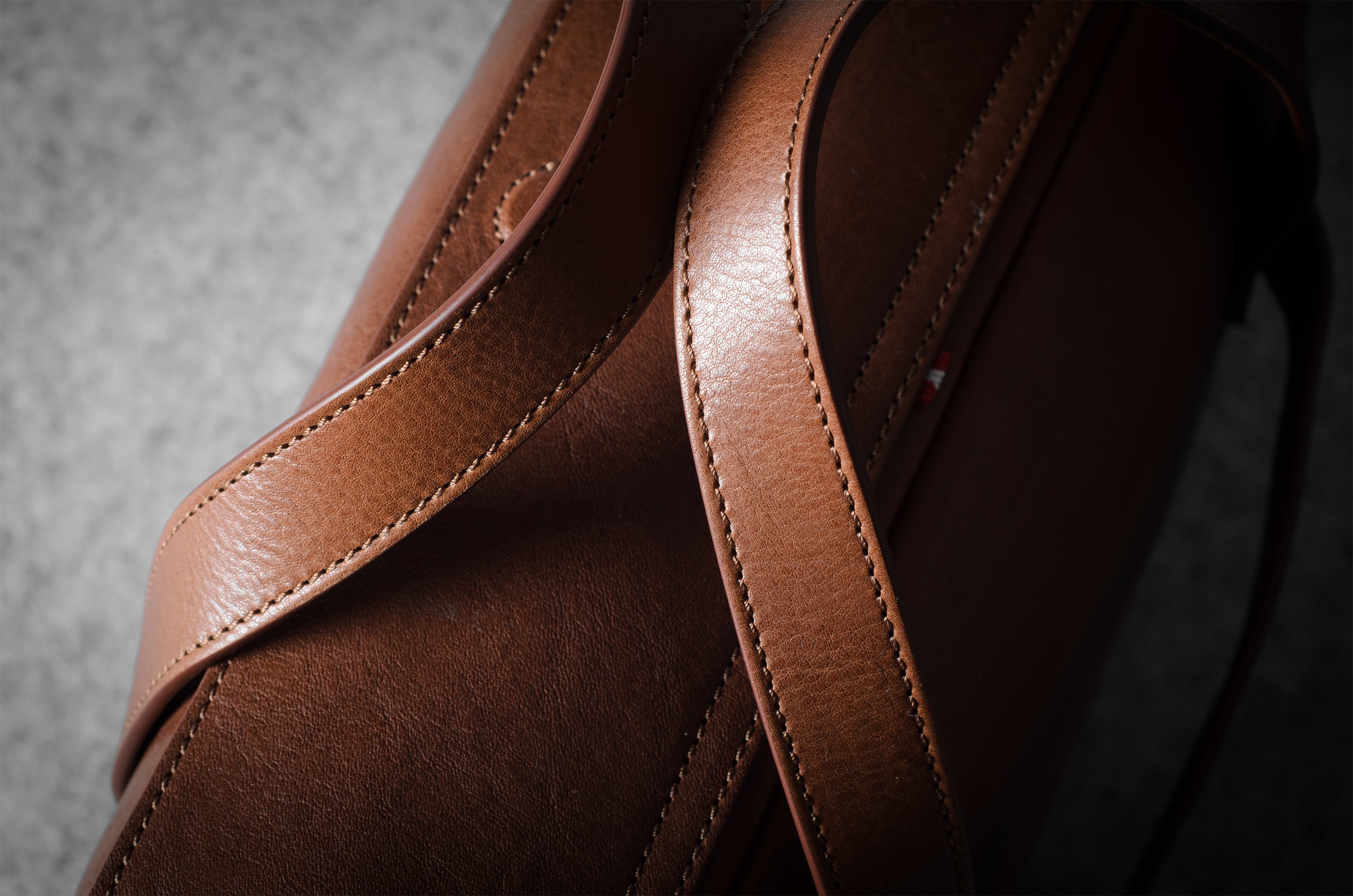 Close-up of a brown leather bag with visible stitching on a dark background