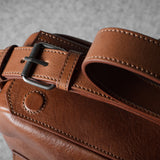 Close-up of a brown leather bag with a buckle on a gray background