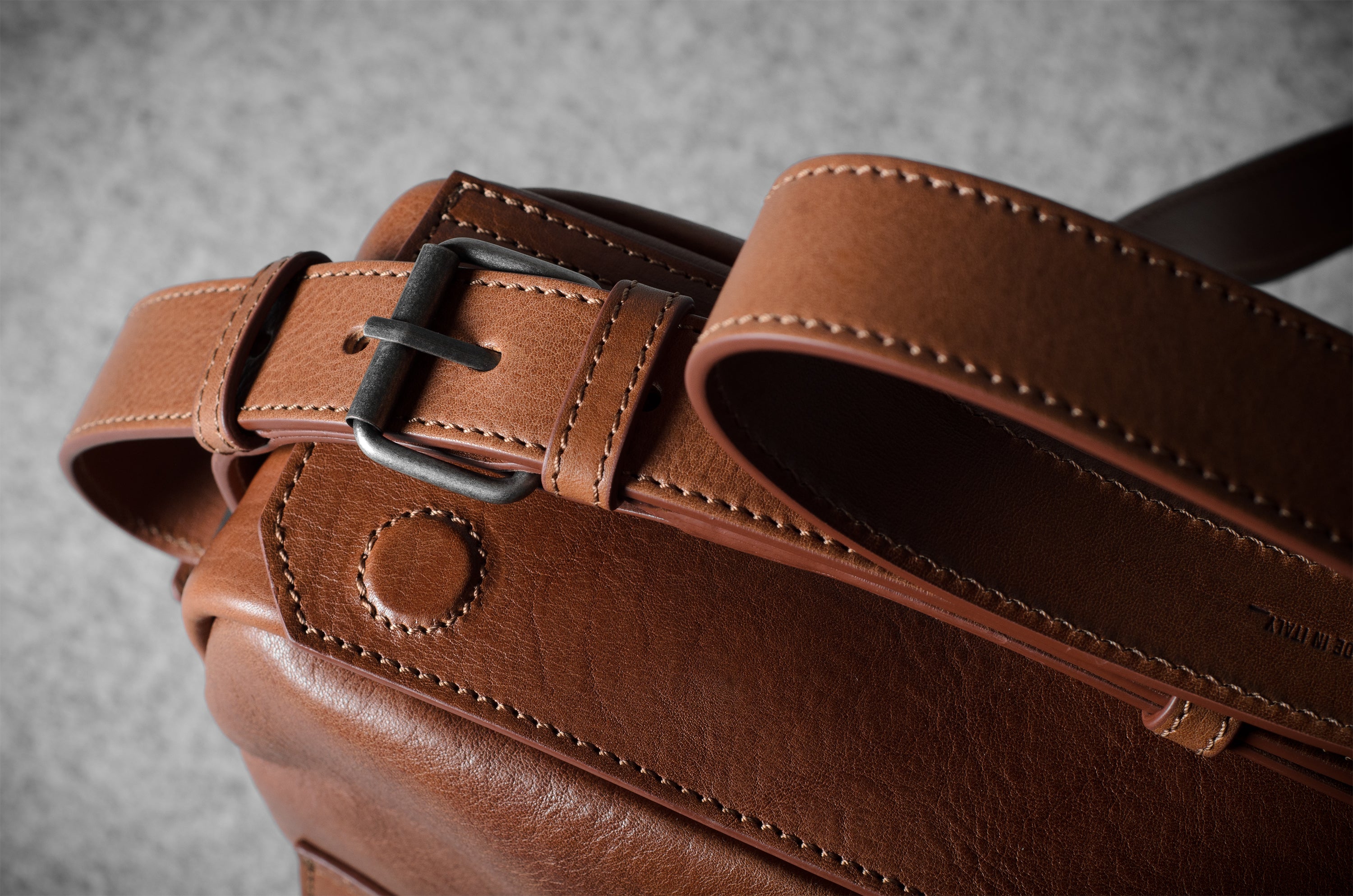 Close-up of a brown leather bag with a buckle on a gray background