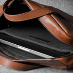 Brown leather bag with a compartment for a laptop on a gray background
