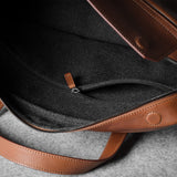 Brown leather bag with a zipper on a gray surface