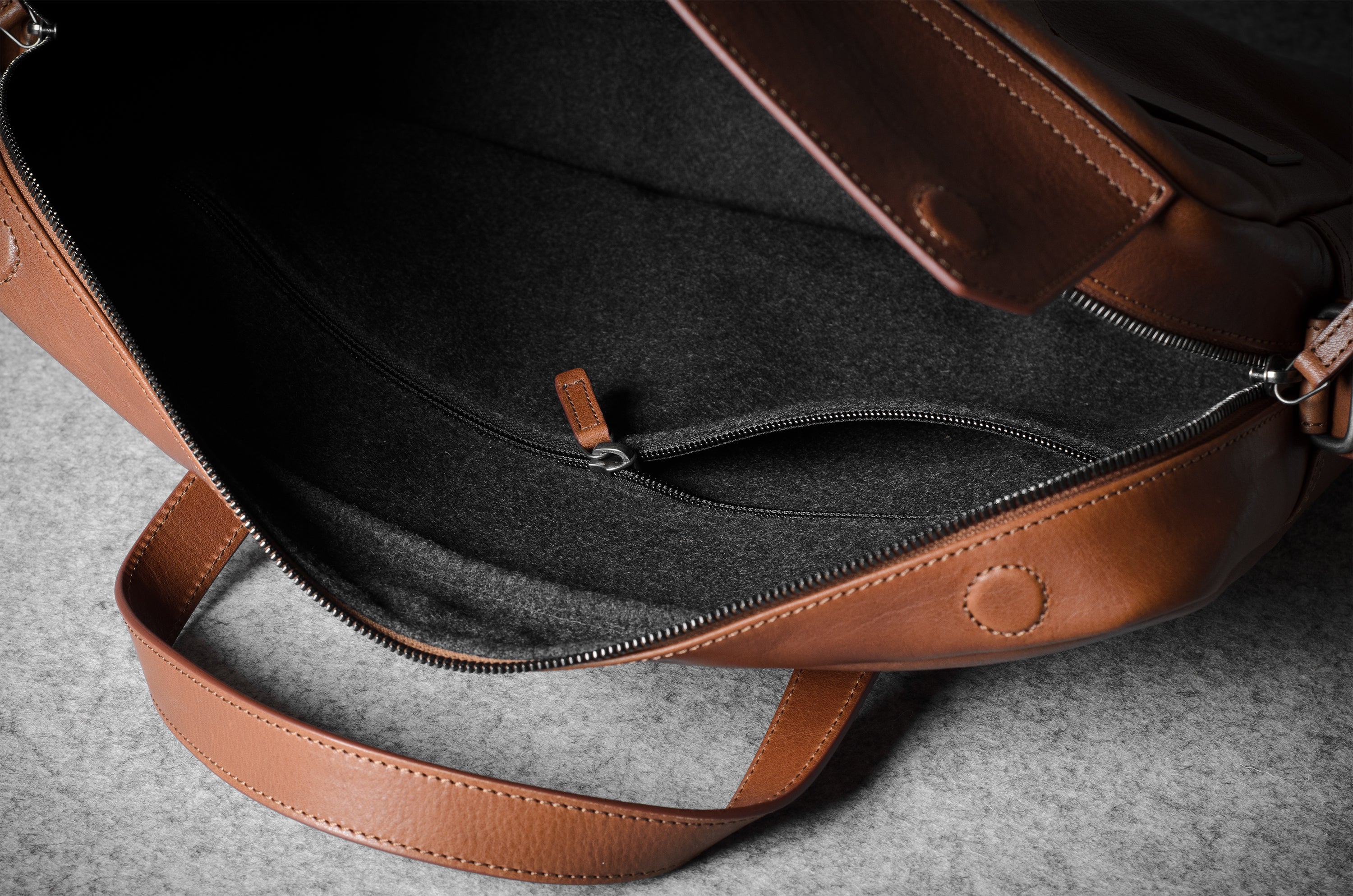 Brown leather bag with a zipper on a gray surface