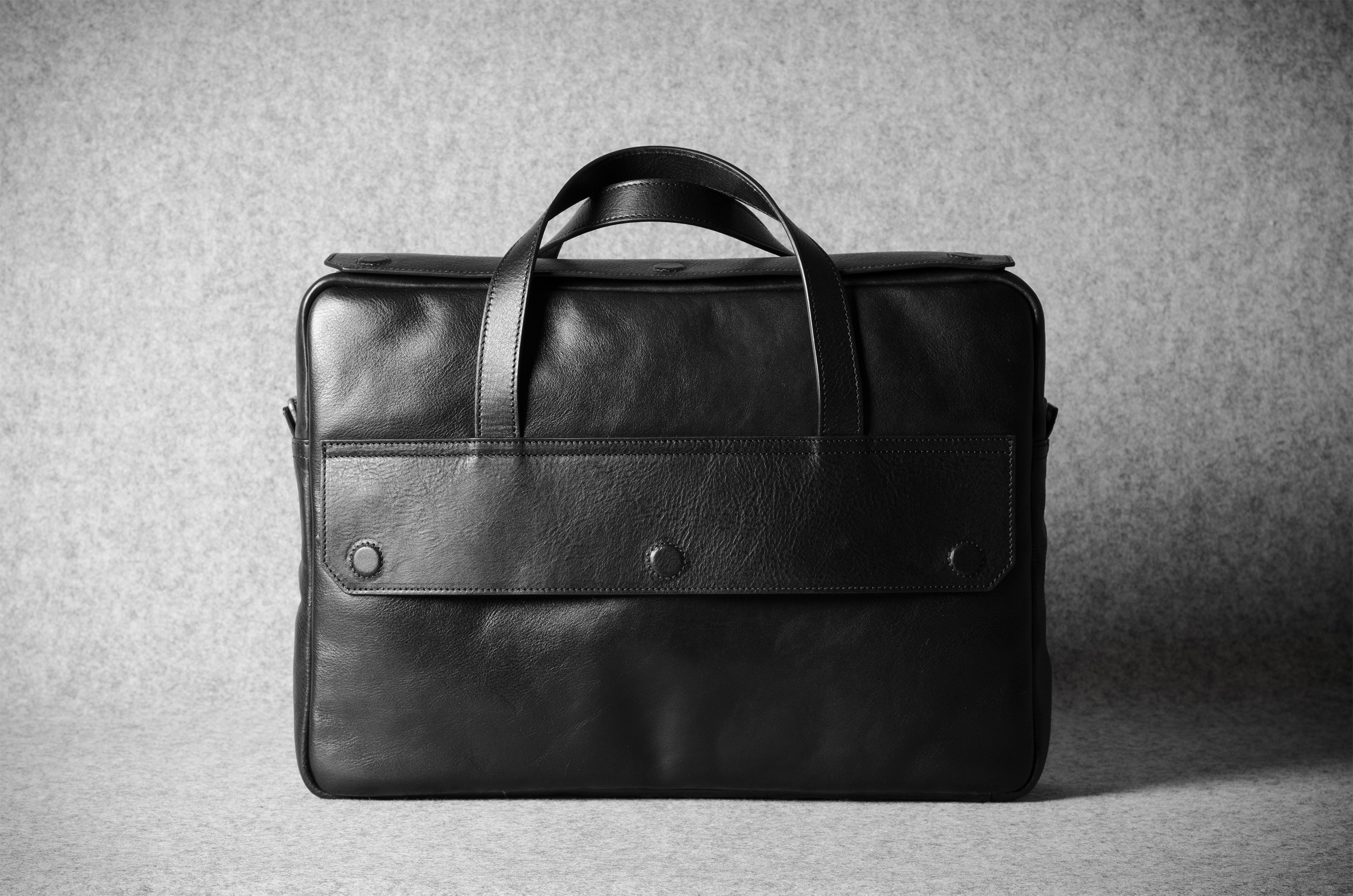 Black leather briefcase on a textured gray background