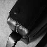 Close-up of a leather bag buckle on a textured gray background