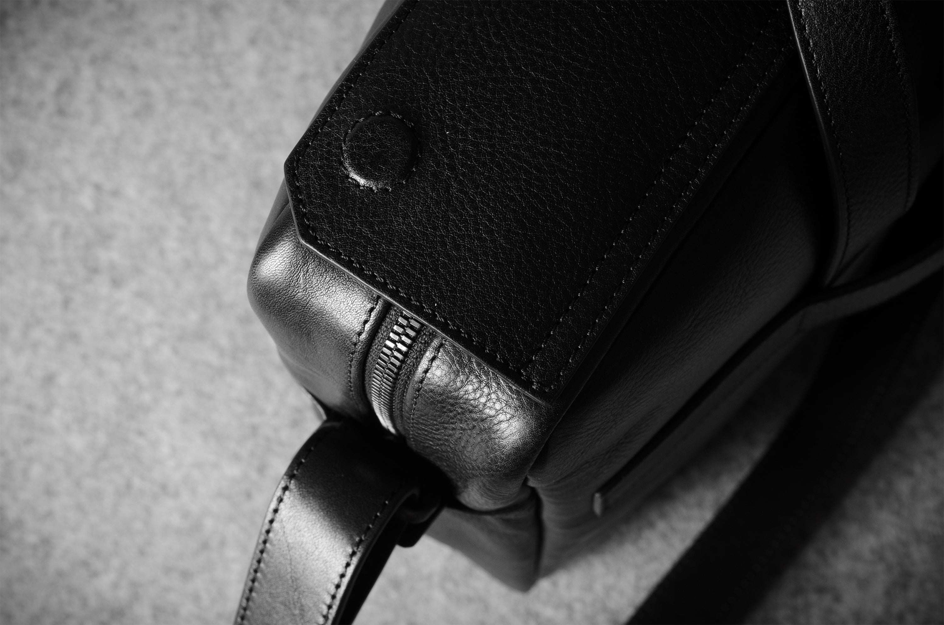 Close-up of a leather bag buckle on a textured gray background