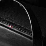 Close-up of a black leather bag with a logo on a dark background