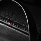 Close-up of a black leather bag with a logo on a dark background