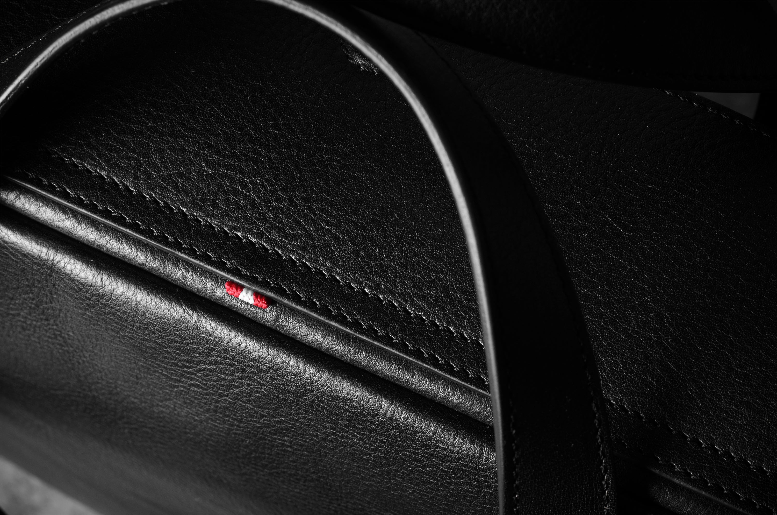 Close-up of a black leather bag with a logo on a dark background
