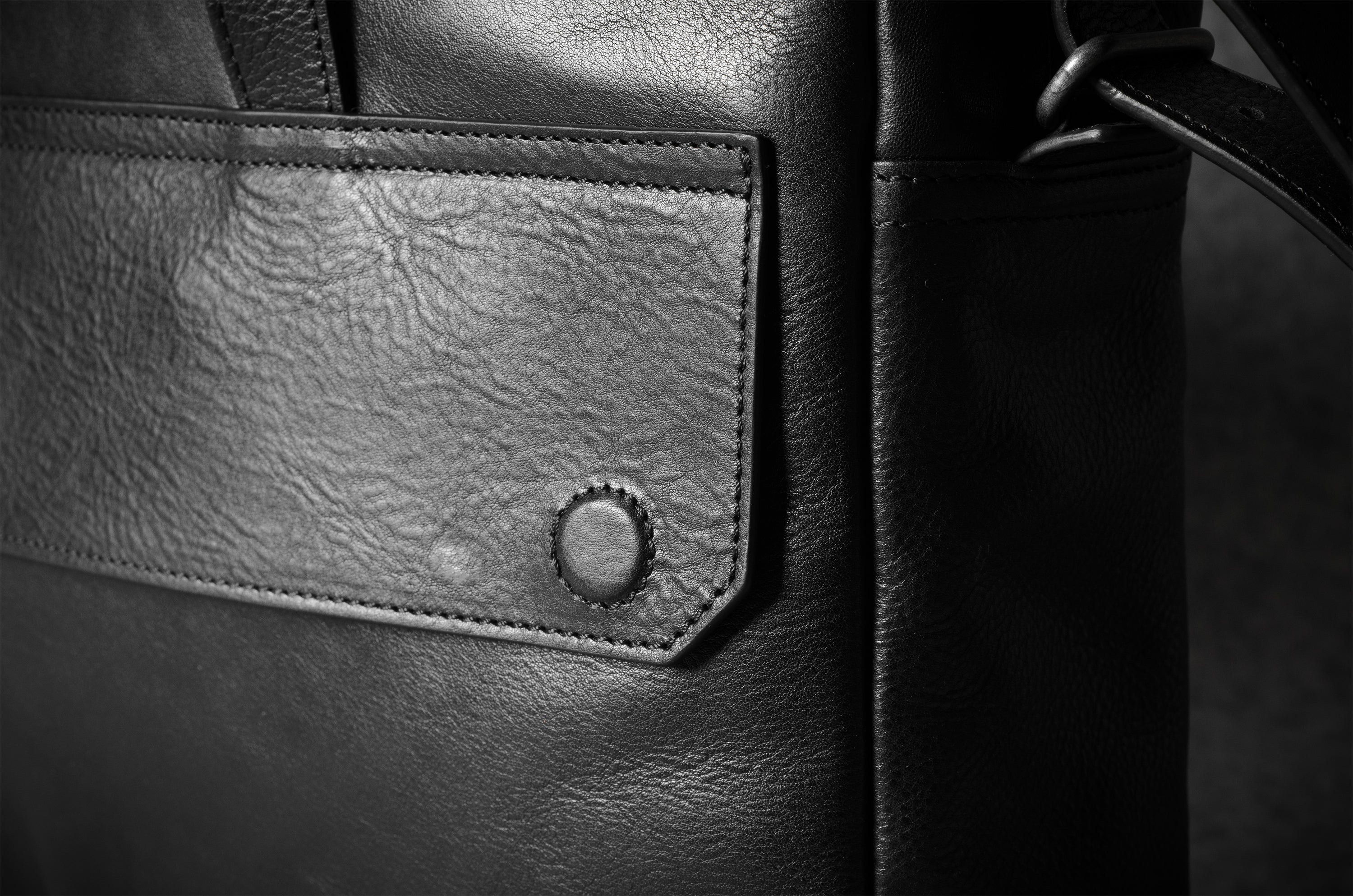 Close-up of a black leather bag with a visible brand patch.