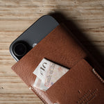 Brown leather iphone case with a banknote on a wooden surface