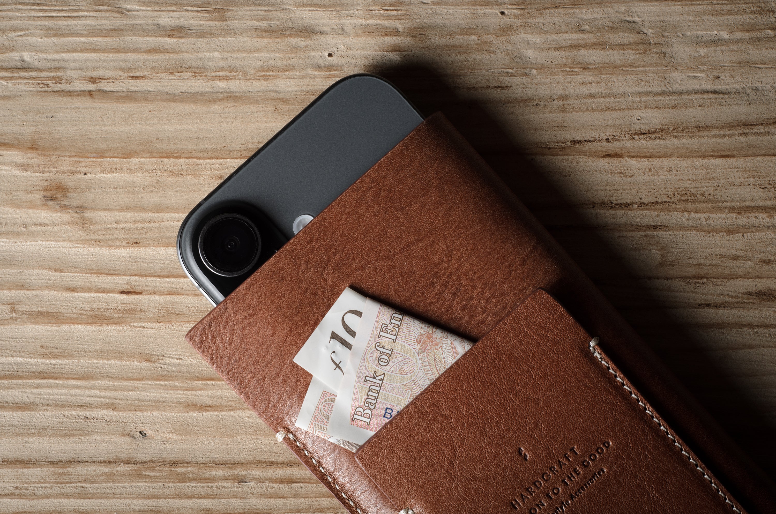 Brown leather iphone case with a banknote on a wooden surface