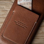Brown leather  iphone case with visible branding on a wooden surface