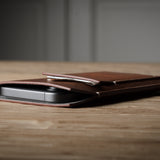Brown leather  iphone case with a phone inside on a wooden surface