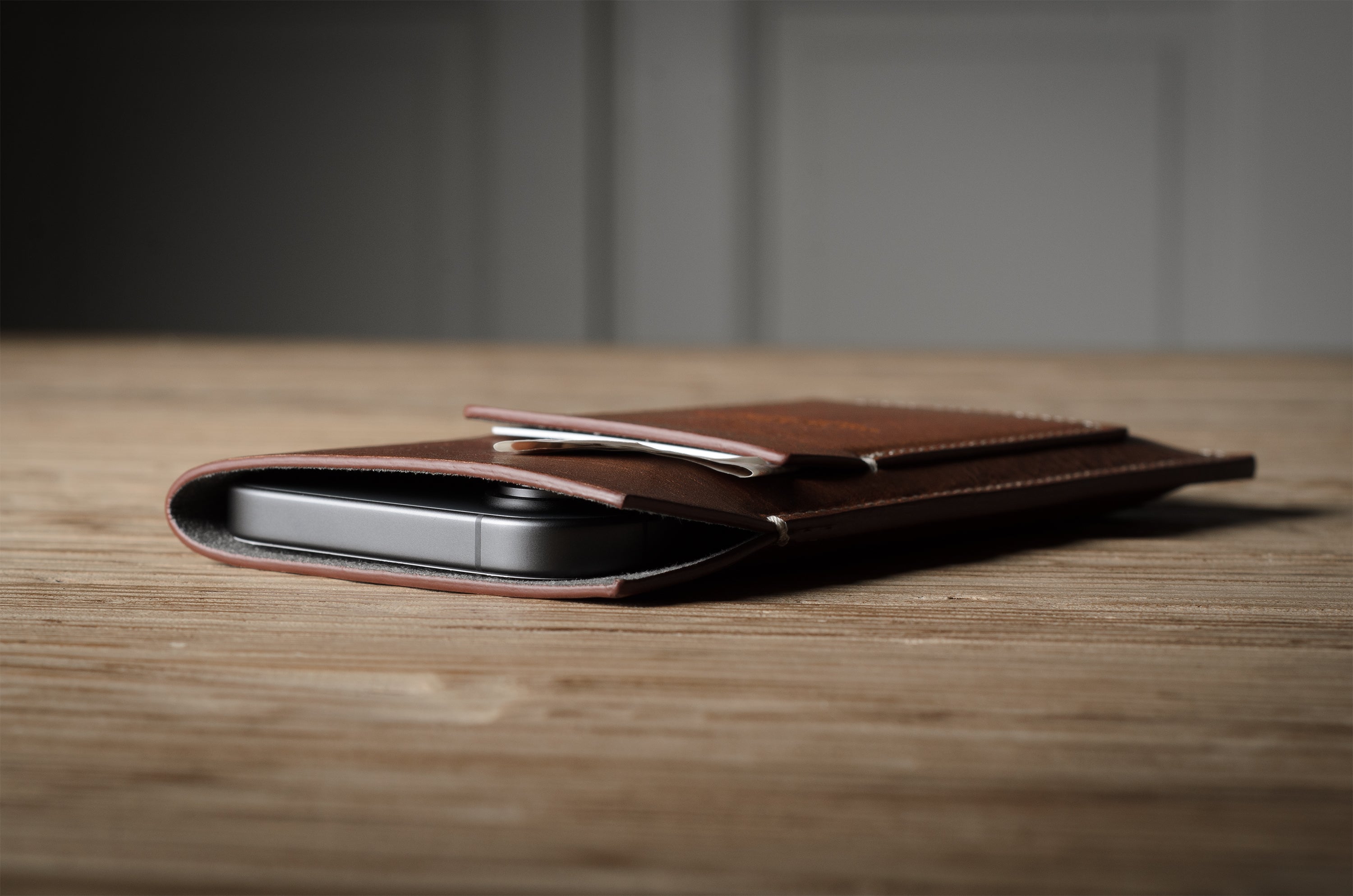 Brown leather  iphone case with a phone inside on a wooden surface