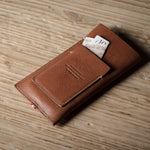 Brown leather  iphone case with a card on a wooden surface