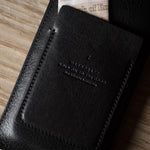 Black leather iphone case with stitching detail on a wooden surface