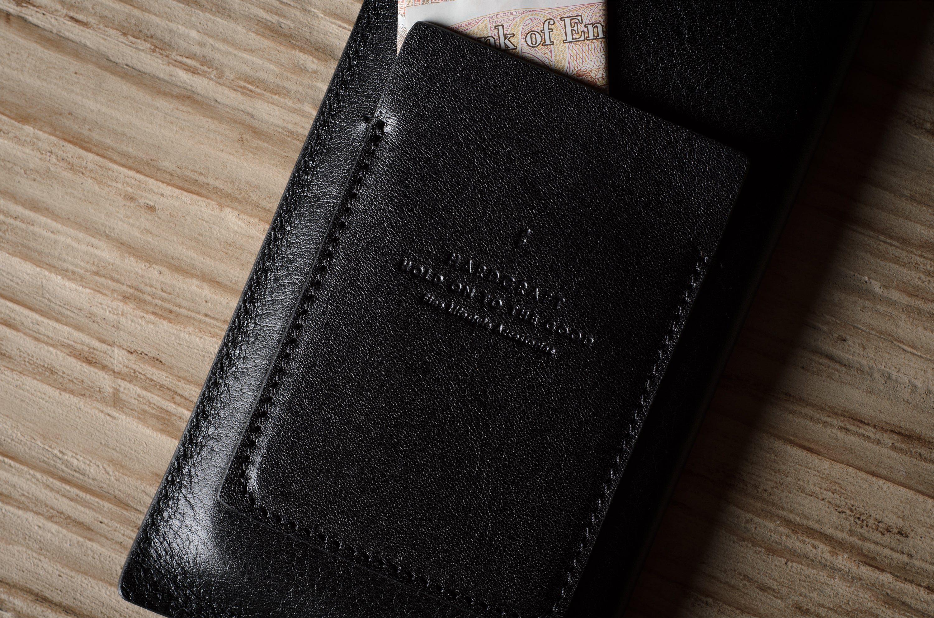 Black leather iphone case with stitching detail on a wooden surface