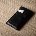 Black leather iphone case with money on a wooden surface