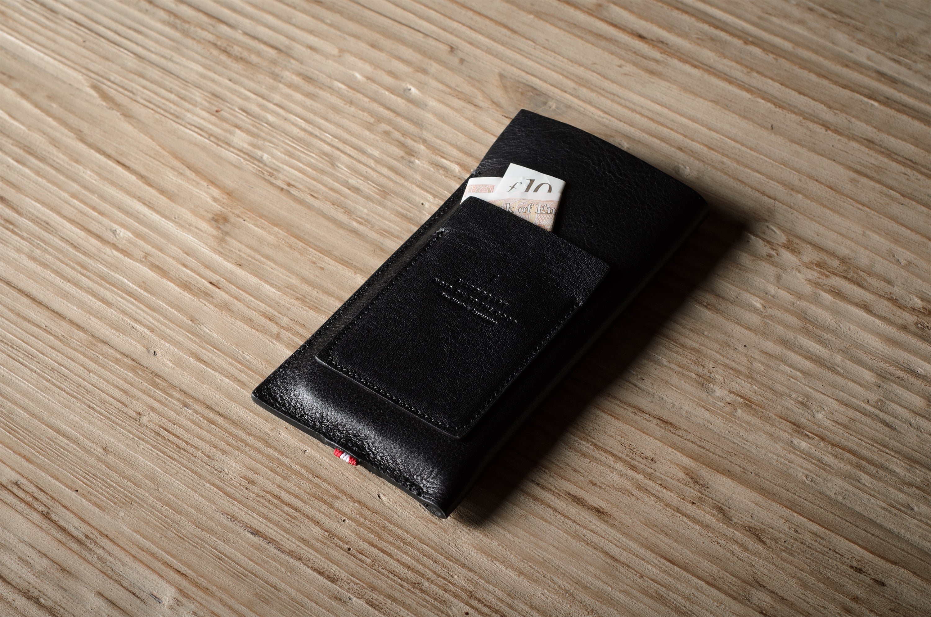 Black leather iphone case with money on a wooden surface